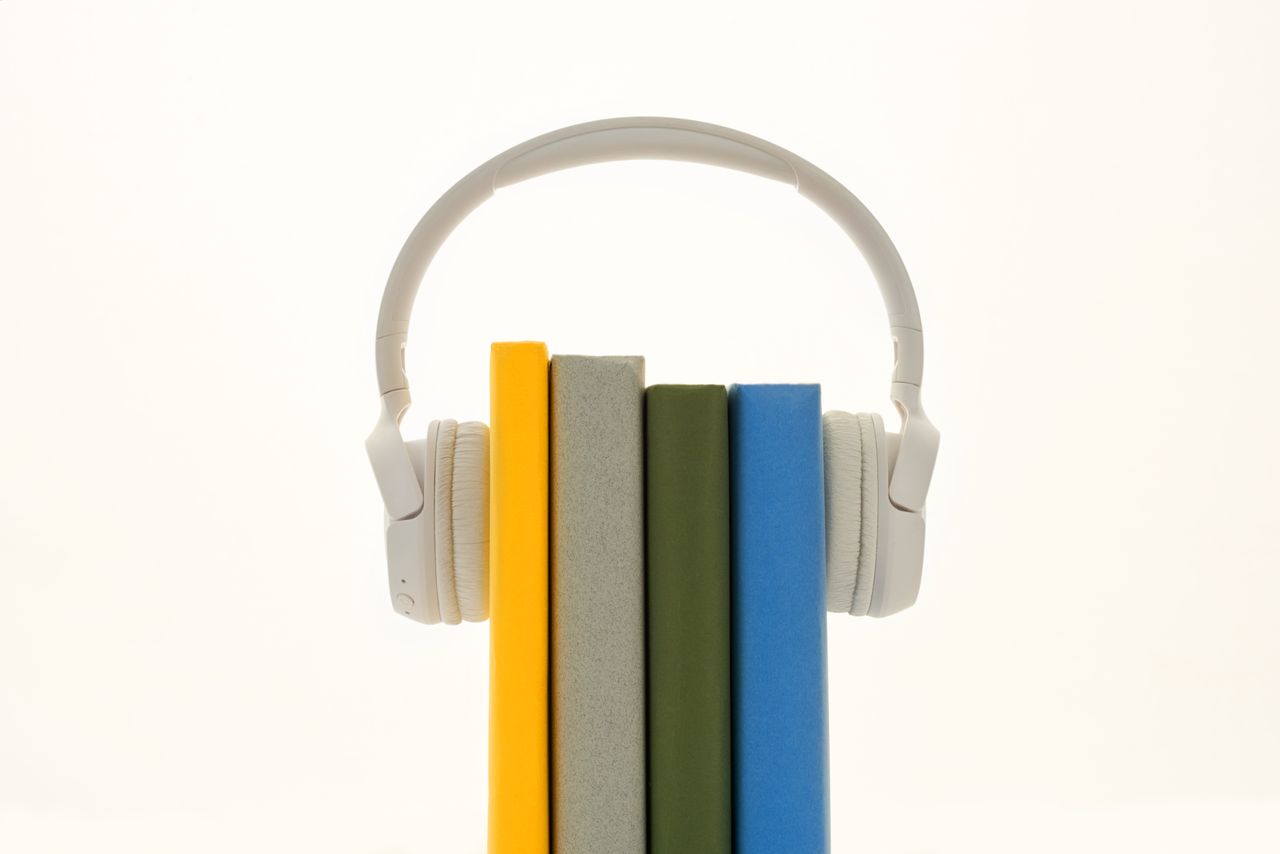 who-we-are White headphones resting on colorful books, symbolizing modern audio technology.